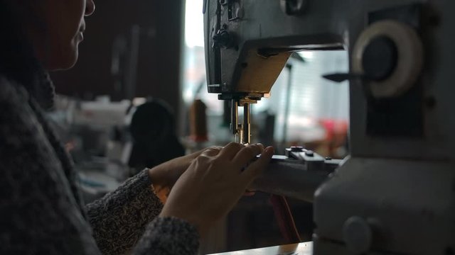 Seamstress working on sewing machine, stitching textile, fabric. Sewing workshop background. Concept for atelier, repairing and tailoring clothes. Handcraft manufacturing. Camera's span