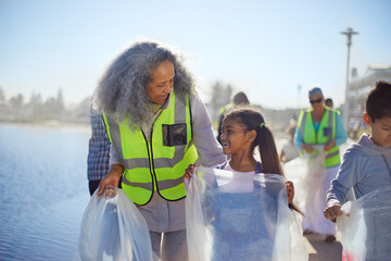 Grandmother granddaughter volunteers picking up litter on boardwalk