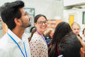 Portrait confident female junior high teacher in library with students