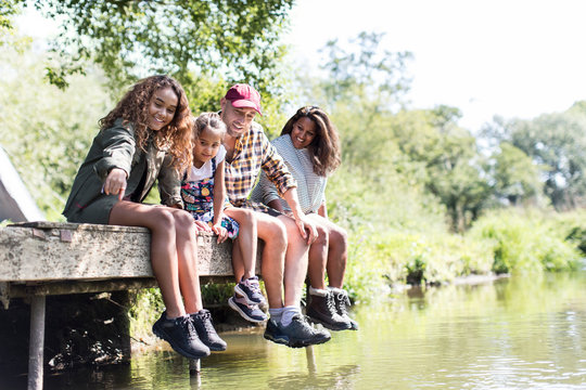 Family sitting on sunny riverside dock