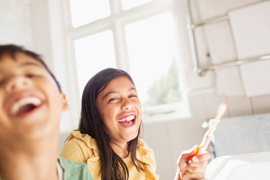 Portrait laughing brother and sister brushing teeth in bathroom