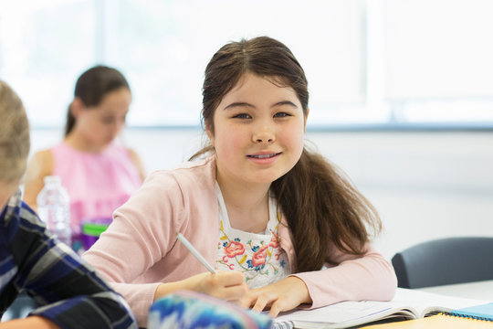 Portrait confident junior high school girl student doing homework in classroom