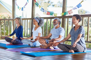 Serene people meditating in hut during yoga retreat