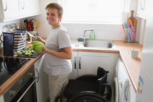 Portrait confident young woman wheelchair cooking in apartment kitchen