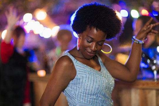 Carefree woman with neon earrings dancing at party