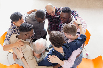 Men hugging in huddle in group therapy