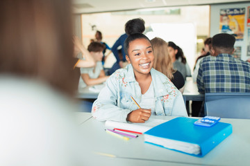 Happy, confident high school girl student studying in classroom