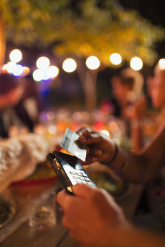 Woman paying with smart card at patio restaurant