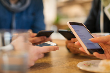 Young adults using smart phones at table