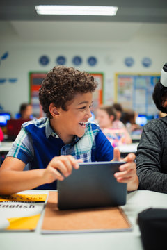 Happy elementary school boy using digital tablet in classroom