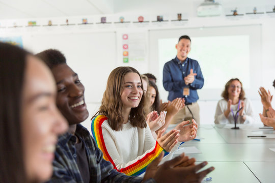 Happy high school students and teacher clapping in debate class