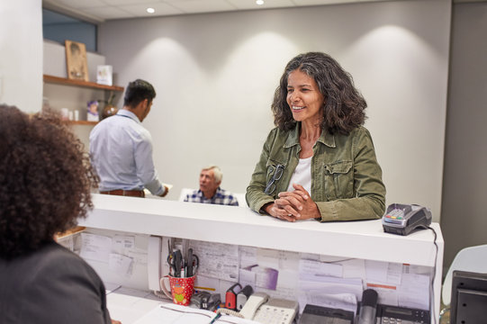 Smiling Woman Checking In At Clinic Reception