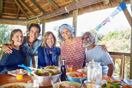 Portrait happy friends enjoying healthy meal in hut during yoga retreat