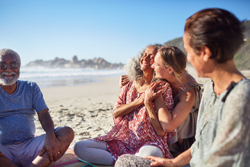 Happy women hugging on sunny beach during yoga retreat