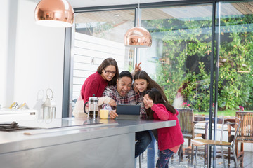 Playful family taking selfie with digital tablet in morning kitchen