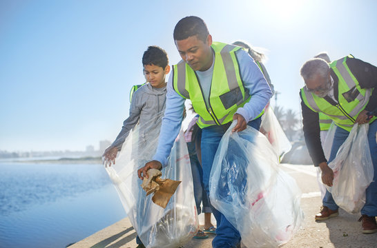 Multi-generation Family Men Volunteering, Picking Up Litter On Waterfront Pier