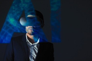 Double exposure businessman with virtual reality simulator glasses against AI text