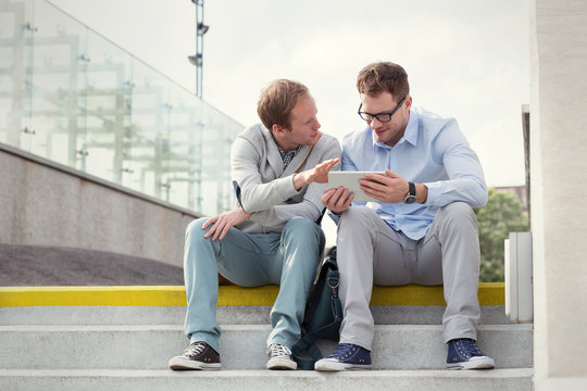 Businessmen talking, using digital tablet on steps