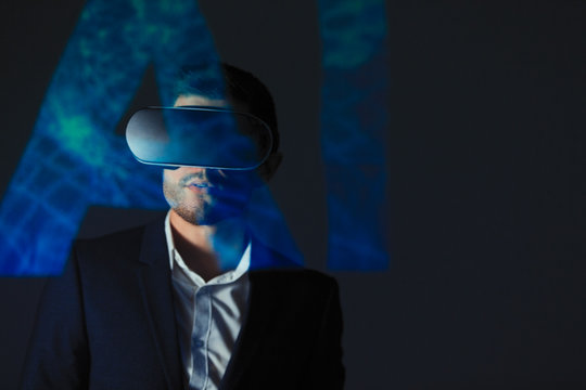 Double exposure businessman with virtual reality simulator glasses against AI text