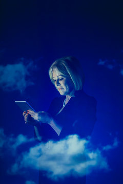 Double exposure businesswoman using digital tablet against blue sky with clouds