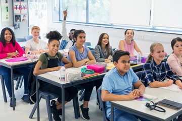 Junior high school students enjoying lesson at desks in classroom