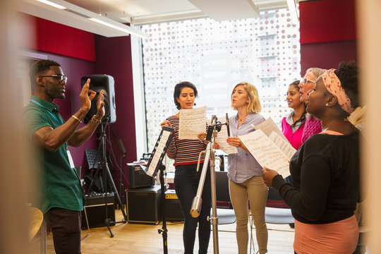 Womens choir with sheet music singing in music recording studio