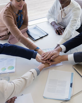 Business people joining hands in conference room meeting