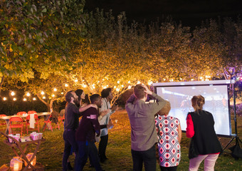 Friends watching basketball game on projection screen in backyard