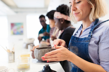 Woman shaping clay bowl in art class