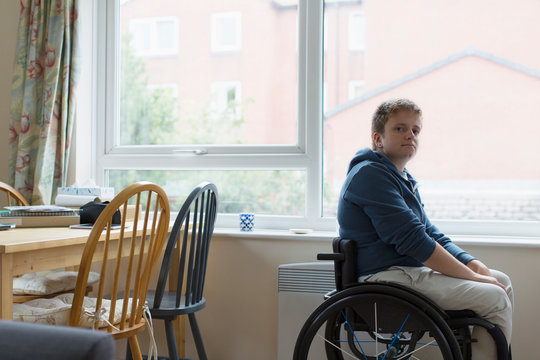Portrait confident young woman sitting in wheelchair at window
