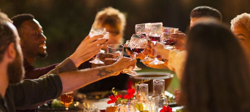 Friends toasting wine glasses, enjoying dinner garden party