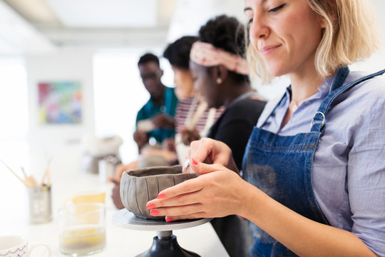 Woman shaping clay bowl in art class