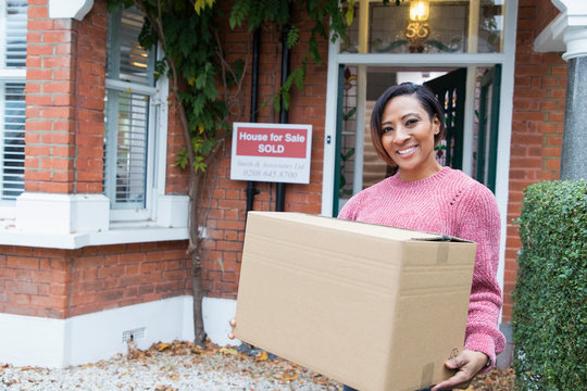 Portrait Smiling, Confident Woman Moving Into New House, Holding Cardboard Box Outside House