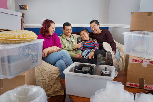 Friends taking a break from moving, using smart phone on sofa