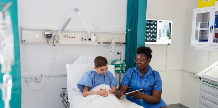 Female nurse talking with boy patient in hospital room