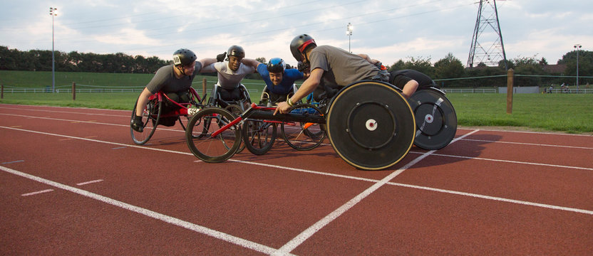 Determined paraplegic athletes bonding in huddle, training for wheelchair race on sports track