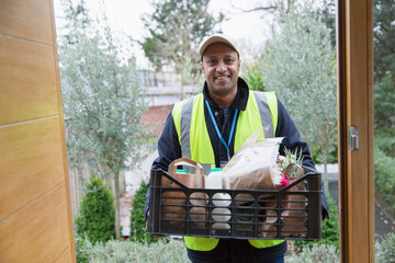 Portrait confident, friendly grocery deliveryman at front door