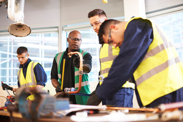 Male instructor and students in shop class workshop