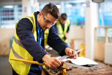 Male student using carpenter rule in shop class workshop