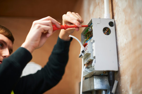Male electrician using screwdriver, working at electric panel