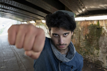 Portrait tough young man punching in urban tunnel