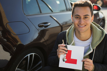 Portrait confident, happy young man holding learners permit by car