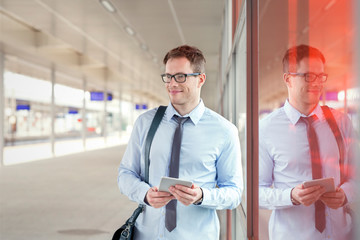 Businessman with digital tablet waiting near train station platform