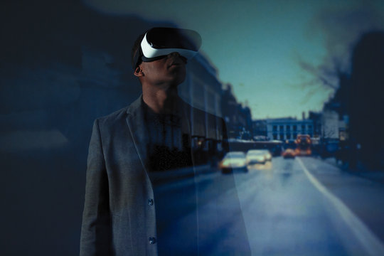Double exposure businessman with virtual reality simulator glasses against city street