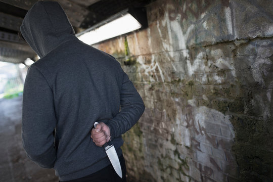 Dangerous man with knife behind back in urban tunnel