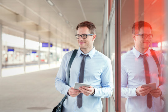 Businessman with digital tablet waiting near train station platform