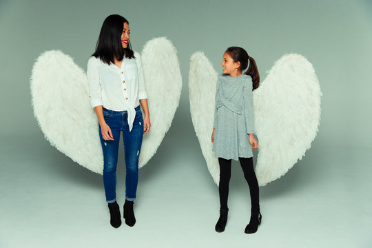 Happy mother and daughter wearing angel wings