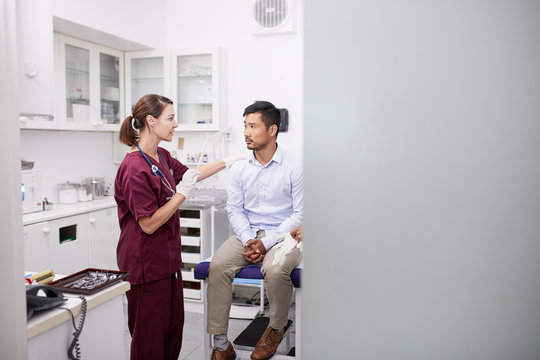 Female doctor talking with male patient in clinic examination room