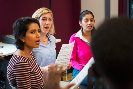 Womens choir with sheet music singing in music recording studio