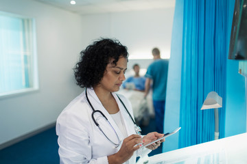 Focused female doctor using digital tablet in hospital room